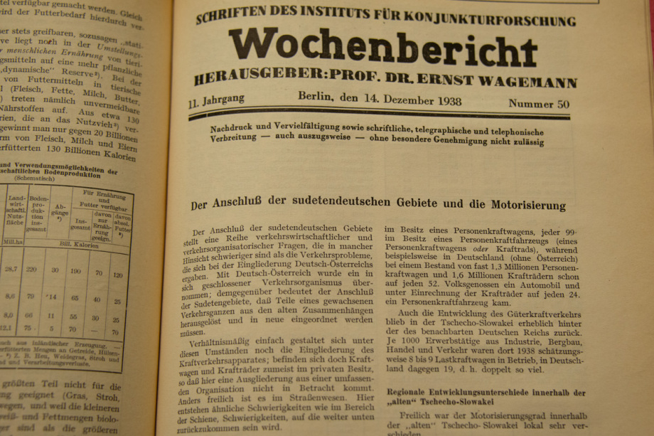 Zu Beginn der NS-Diktatur veröffentlichte das DIW seine Wochenberichte mit Forschung im Sinne der Nazis. In seinen Wochenberichten rechneten die DIW-Wissenschaftler vor, wie gut die Kriegswirtschaft gedeihe, beispielsweise indem sie 1938 aufschrieben, wie die NS-Wirtschaft nach fünf Jahren aussieht.; Titel: Wochenbericht vom 14. Dezember 1938<br />
Beschreibung: Das Bild zeigt eine aufgeschlagene Seite eines historischen Dokuments oder einer Zeitschrift mit dem Titel "Wochenbericht". Der Text ist in deutscher Sprache verfasst und stammt aus dem Jahr 1938. Die Überschrift lautet: "Wochenbericht Herausgeber: Prof. Dr. Ernst Wagemann". Darunter steht das Datum "Berlin, den 14. Dezember 1938" und die Ausgabe Nummer "50".<br />
Der Hauptartikel auf der Seite trägt den Titel: "Der Anschluß der sudetendeutschen Gebiete und die Motorisierung". Der Artikel beginnt mit einem Absatz, der über den Anschluss der sudetendeutschen Gebiete an das Deutsche Reich berichtet.<br />
Auf der linken Seite des Bildes ist ein Teil einer Tabelle zu sehen, die verschiedene Daten enthält.