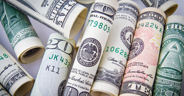 Auf dem Bild sind zusammengerollte Dollar-Geldscheine zu sehen. 