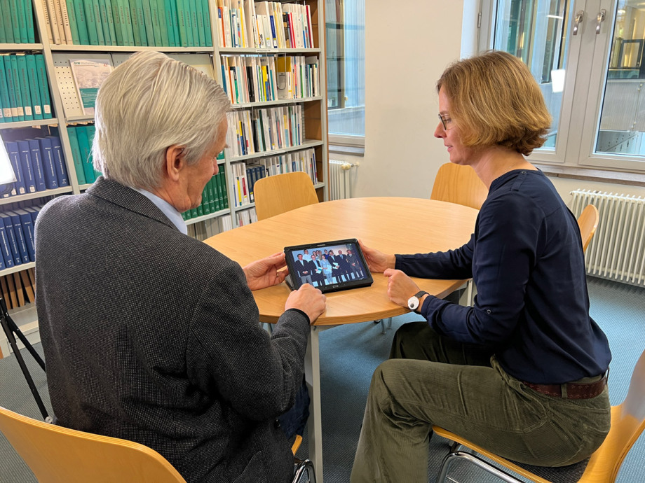 Georg Meran (links) und Kerstin Bernoth betrachten Fotos der ersten Absolvent*innen des Graduate Centers.; 