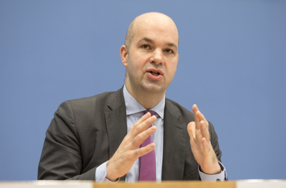 Auf dem Foto ist Marcel Fratzscher, Präsident des DIW Berlin, bei einer Pressekonferenz im Haus der Bundespressekonferenz zu sehen. Er gestikuliert mit den Händen und sitzt vor einer blauen Wand.