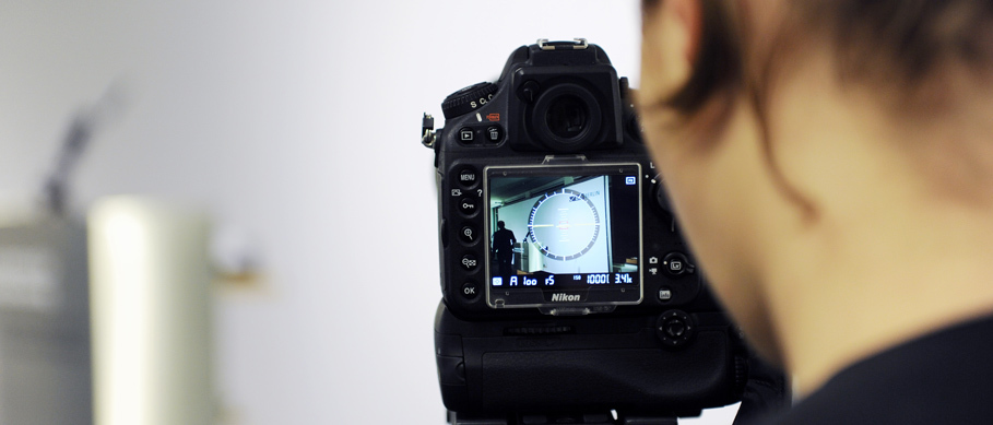 Eine Frau schaut durch eine Fotokamera auf die zu filmende Bühne.