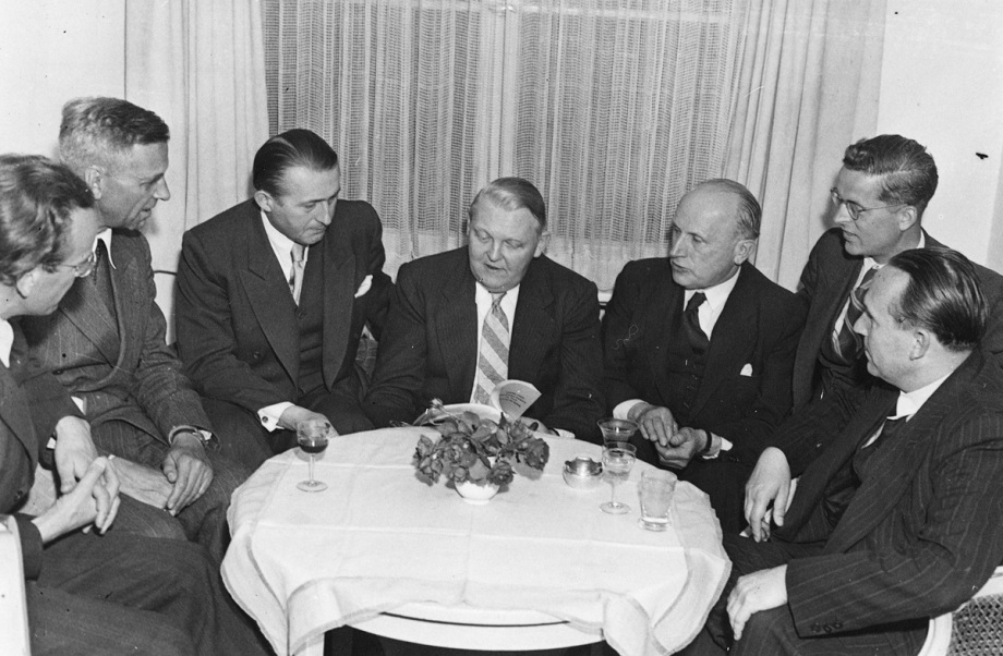 Ferdinand Friedensburg (3.v.r.) 1949 im Gespräch mit Ludwig Erhard (Mitte), der damals noch Direktor der Wirtschaftsverwaltung der US-amerikanischen und britischen Bizone war. Später wurde Erhard Bundeswirtschaftsminister.; An einem Tisch sitzen sieben Männer in Anzügen. In der Mitte sitzt Ludwig Erhard, damals Direktor der Wirtschaftsverwaltung der US-amerikanischen und britischen Bizone , rechts neben ihm sitzt DIW-Präsident Ferdinand Friedensburg