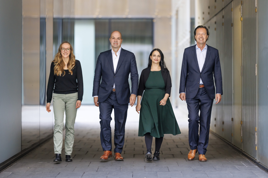 Der Vorstand des DIW Berlin (v.l.n.r.) Denise Rüttinger, Marcel Fratzscher, Sabine Zinn, Alexander S. Kritikos; Vier Personen in Geschäftskleidung stehen nebeneinander in einem modernen Gebäude mit Glaswänden im Hintergrund. Zwei Männer und zwei Frauen lächeln und wirken professionell. Der Hintergrund zeigt eine helle, moderne Architektur mit großen Fenstern und einer Tür.