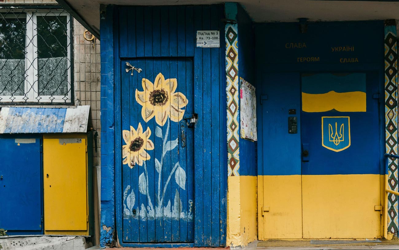 Auf dem Bild ist ein Hauseingang mit den Farben und Symbolen der ukrainischen Nationalfahne zu sehen. Das Haus befindet sich in der ukrainischen Hauptstadt Kiew.